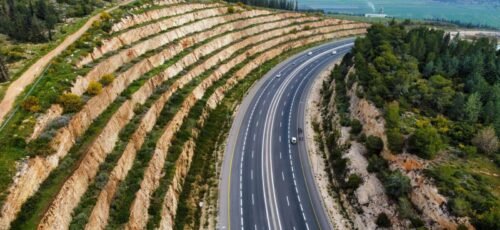 Stunning aerial view of a highway winding through terraced hills and lush greenery.
