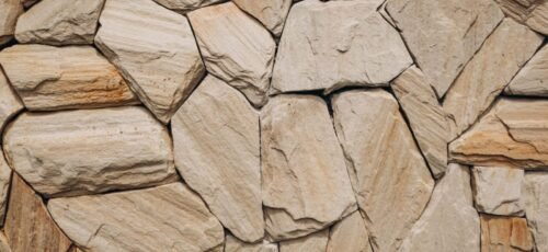 Detailed natural stone wall texture showcasing uneven rocks in beige tones.